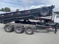 A black 2014 PJ 16 foot dump trailer is raised at an angle with three wheels visible under the trailer and a spare tire mounted on the side