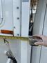 A hand holds a measuring tape against the side of a 2018 Westland Travelaire trailer with markings visible along the tape