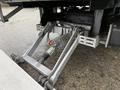 A close-up of the suspension system of a 2024 Ford E-450 showing metal components and hydraulic lines attached to a large vehicle chassis