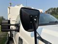 A close-up of the side mirror of a 2009 Ford F-550 with a black housing and a chrome bolt visible on a white truck