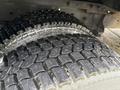 Close-up view of two large, heavy-duty tires with a deep tread pattern, showing wear and dirt on the sidewalls and treads