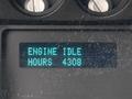 Display screen showing "ENGINE IDLE" and "HOURS 4308" on a dashboard panel of a vehicle