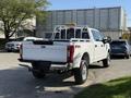 A white 2021 Ford F-250 Super Duty pickup truck with a bed rack and visible FX4 badge parked with its rear facing the viewer