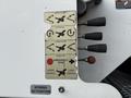 A control panel with labels for upper boom rotation lower boom and emergency stop on a 2015 Freightliner M2