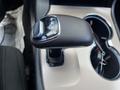 A gear shift lever of a 2015 Jeep Grand Cherokee with a leather-covered handle showing P R N D S markings