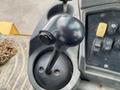A black control joystick from a 2012 John Deere 310SJ machinery with a circular base and a smooth top surface