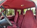Interior view of a 1995 Ford F-250 showcasing red upholstery with two front seats and dual armrests