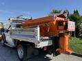 A 2011 Ford F-550 truck with an orange salt spreader attached to its rear and a sign indicating to keep back 20 meters