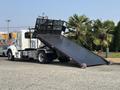A 2020 Peterbilt 330 flatbed truck with a lowered ramp and a distinctive black loading surface