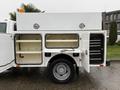 A 2015 Ford F-450 truck with an open utility bed featuring compartments and drawers for storage