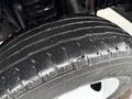 Close-up of a 2022 Ford Econoline tire featuring a worn tread pattern and slight moisture on the surface