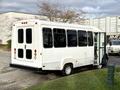 A white 2002 Ford Econoline van with an open side door and multiple rear windows parked on a surface with grass