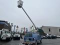 A blue 2006 Ford Econoline van with a raised aerial work platform mounted on its roof