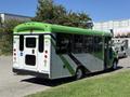 A green and white 2013 Chevrolet Express shuttle bus with wheelchair accessibility features parked on a driveway