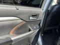 The interior of a 2018 Toyota Highlander featuring a driver's side door panel with a combination of black and brown trim and control buttons for windows and locks