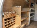 Interior of a 2008 Ford Econoline van featuring wooden shelves and a compartment with small cubbies for storage
