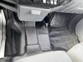 The interior floor of a 2015 Ford F-550 showing a textured rubber mat with a molded design and a cup holder attached to the dashboard