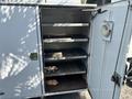 An open storage compartment with metal shelves inside a 2006 International 4300 truck