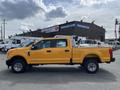 A 2017 Ford F-250 SD in bright yellow with a crew cab and a flatbed truck bed is parked with a side view displaying its large wheels and sturdy build