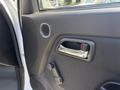 Close-up of the interior door panel of a 2011 Chevrolet Colorado featuring a door handle a speaker and a manual window control knob