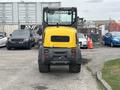 A yellow and gray 2014 Wacker Neuson WL34 wheeled loader facing forward with large tires and a cabin visible