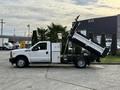 A 2015 Ford F-350 with a flatbed and dump feature raised, showcasing the truck's heavy-duty construction and functionality