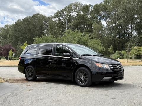 A black 2014 Honda Odyssey minivan parked with a sleek design and dark wheels