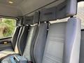 Interior view of a 1999 Freightliner FL80 truck featuring grey cloth seats with headrests and a low dashboard area visible in the foreground