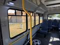 Interior view of a 2017 Chevrolet Express featuring blue upholstered seats a yellow handrail and windows showing an outdoor scene