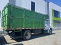 A green 1997 Freightliner FL70 truck with a large boxy cargo area and dual rear wheels parked in a lot