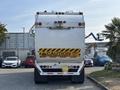 A white 2011 Autocar Xpeditor garbage truck viewed from the rear with caution signs indicating vehicle stops and backs frequently