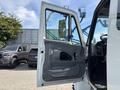 A 2006 International 4300 truck with the driver's door open showcasing the interior features and controls