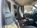 Interior view of a 2011 Chevrolet Express showing the driver's seat and dashboard with controls and storage compartments visible