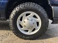 A close-up of a Goodyear tire mounted on a silver wheel with five spokes, part of a 2013 Ford E-350 Super Duty vehicle