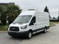 A 2017 Ford Transit van with a white exterior and a black stripe along the lower side, featuring a roof-mounted unit and front grille with the Ford logo