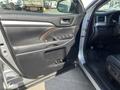 The interior door panel of a 2018 Toyota Highlander featuring controls for windows and locks with a wood trim accent