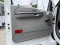 The interior door panel of a 2004 Ford F-750 featuring a gray handle a speaker grille and textured lower section