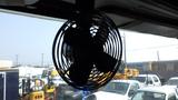 A black circular fan with five blades mounted inside a cab of a 2003 International 5600i