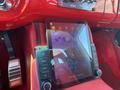 A dashboard featuring a large touchscreen display with buttons on either side in a red interior setting