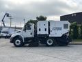 A 2012 International DuraStar 4300 street sweeper with a white body and a large attached vacuum unit on the rear side