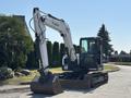 A 2010 Bobcat E80 excavator with a large bucket attached to its front arm and tracks for movement