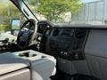 Interior view of a 2015 Ford F-550 featuring a steering wheel dashboard audio controls and gear shifter with gray upholstery and black accents