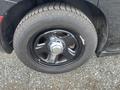 Black wheel of a 2015 Dodge Charger with a shiny silver hubcap and thick rubber tire visible
