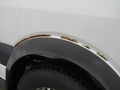 A 2009 Dodge Sprinter Van showing rust damage along the wheel arch area with a black tire visible in the foreground