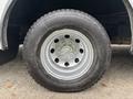 A close-up of a wheel and tire from a 2012 Ford E-450 Super Duty showing a silver rim with multiple holes and a rugged black tire tread
