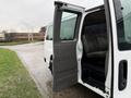 A white 2021 Chevrolet Express van with an open side door revealing a spacious interior and seating arrangement