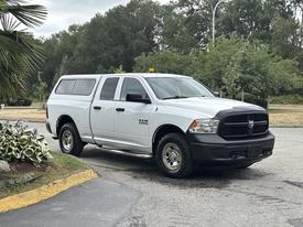 A 2013 RAM 1500 pickup truck in white with a black front grille and chrome wheels parked on a lot