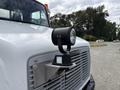 A 1998 Freightliner FL80 with a mounted spotlight on the front, showcasing its distinct grille and hood design