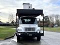 A 2015 Freightliner M2 truck with a flatbed design featuring a large white cargo unit positioned on top of the truck's bed