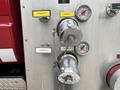 Close-up of a 2002 GMC C7500 fire engine's discharge controls with metal gauges and valves labeled for water discharge operations